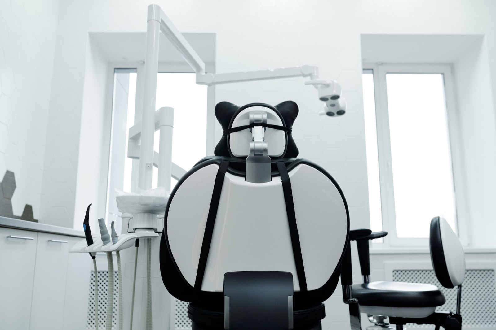 Bright, modern dental operatory with a dental chair and overhead equipment in a well-lit clinic.