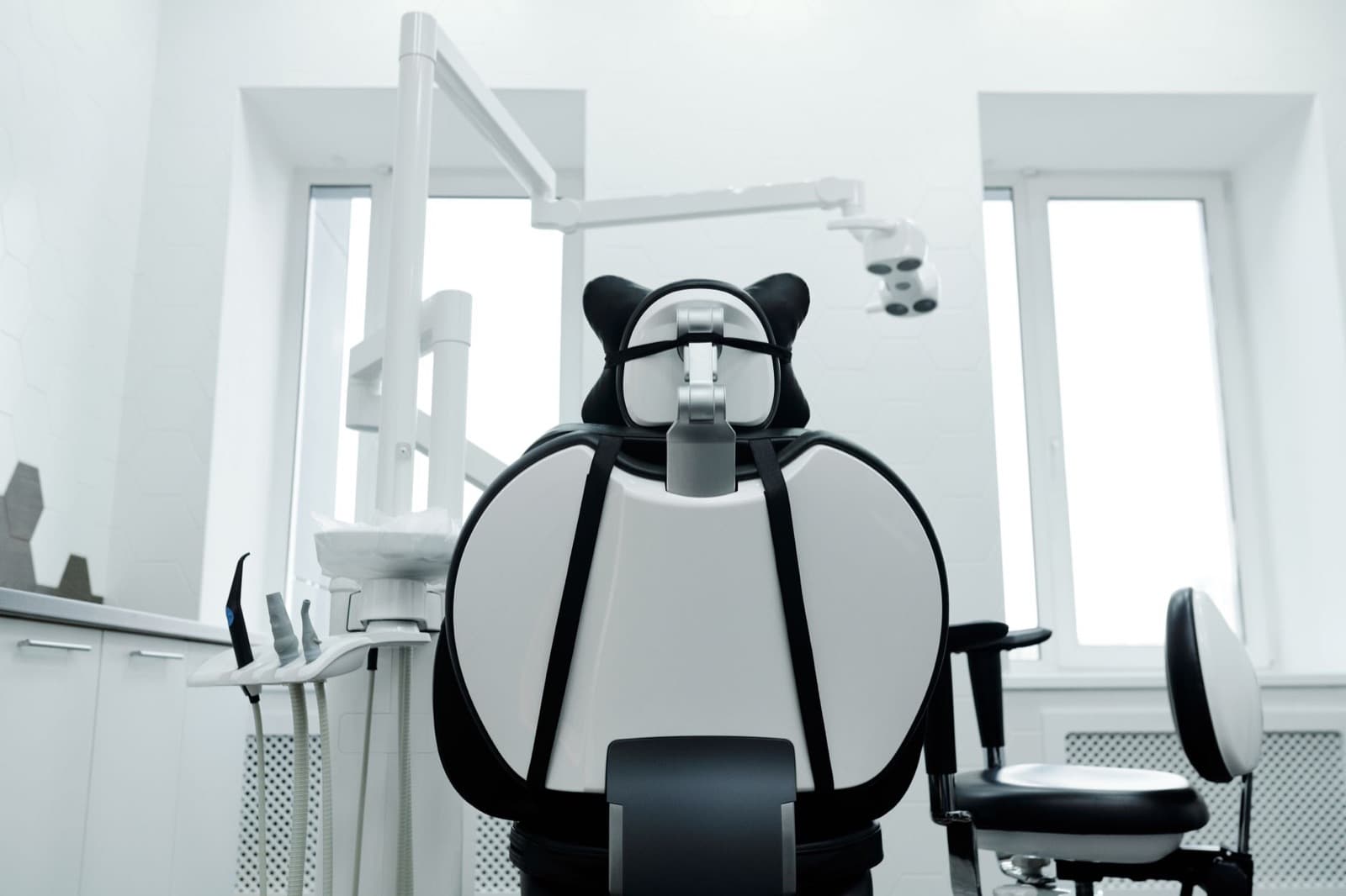 Bright, modern dental operatory with a dental chair and overhead equipment in a well-lit clinic.