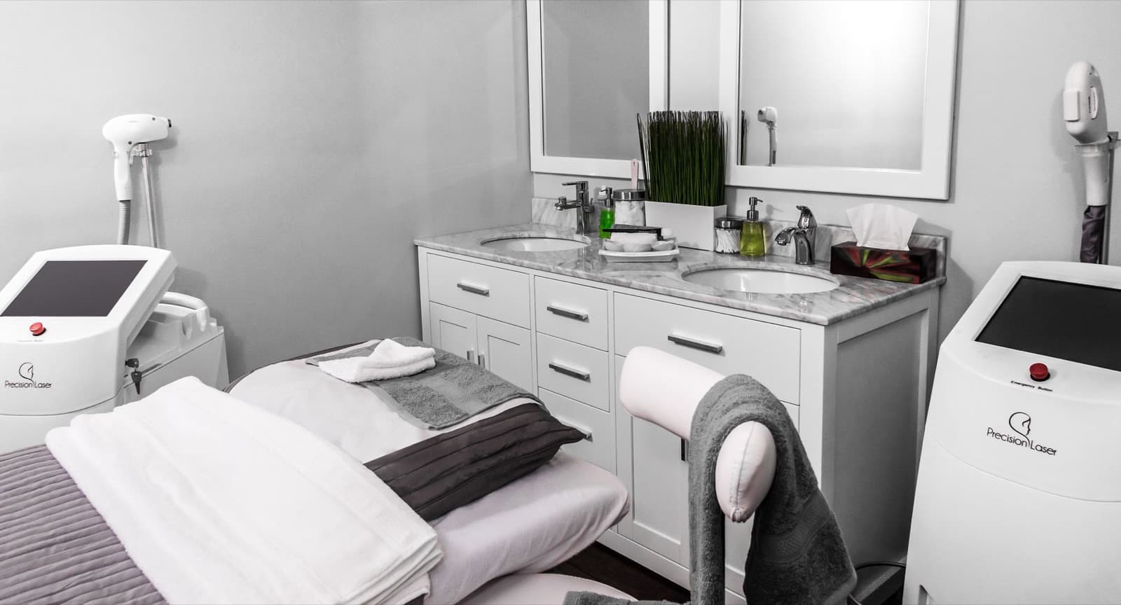 Clean aesthetic clinic treatment room with a prepared table, marble vanity, and laser equipment.